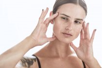 Mulher séria com maquiagem e sardas no nariz tocando suavemente a pele e olhando para longe — Fotografia de Stock