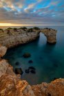 Dall'alto pittoresca vista delle alte formazioni rocciose sulla costa oceanica sotto il cielo del tramonto a Praia da Abandeira, Algarve Portogallo — Foto stock
