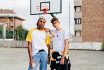 Dois adolescentes de pé e olhando para a câmera na quadra da cesta urbana — Fotografia de Stock