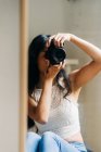 Langhaarige brünette Frau schaut in den Spiegel — Stockfoto