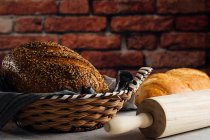Delicioso pão integral em cesta de palha na mesa — Fotografia de Stock