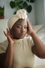 Wunderschönes junges afrikanisches Model in stylischem traditionellen Turban sitzt zu Hause vor dem Spiegel — Stockfoto