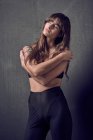 Sinnliche Frau mit Tätowierung mit BH am Hals steht im Studio vor schwarzem Hintergrund — Stockfoto
