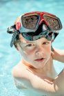 Чарівний маленький хлопчик у снорклінг окулярах, який плаває у відкритому басейні перед тренуванням з дайвінгу в сонячний день — стокове фото