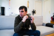 Masculino com deficiência visual rolando telefone celular enquanto sentado no sofá em casa — Fotografia de Stock