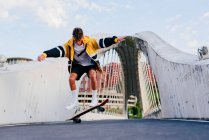 Kaukasischer Teenager springt mit Skateboard mitten auf der Brücke in der Stadt — Stockfoto