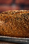 Gros plan de pain coupé savoureux avec croûte brune et graines de tournesol croquantes sur le dessus dans un panier en osier — Photo de stock