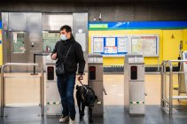 Ganzkörper-Männchen mit medizinischer Maske läuft mit Hund in U-Bahn durch automatisches Kartenlesegerät — Stockfoto