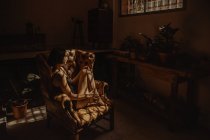 Вид сбоку мирной женщины в ночном халате, сидящей в кожаном кресле, освещенном солнцем и расслабляющей с закрытыми глазами — стоковое фото