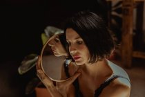 Friedliche Frau sitzt auf dem Boden im Raum und reflektiert in einem runden Spiegel — Stockfoto