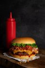 Detail of a delicious burger with cheese and bacon on the wooden table — Stock Photo