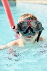 Очаровательный мальчик в очках для подводного плавания плавает в открытом бассейне перед дайвингом тренировки в солнечный день — стоковое фото