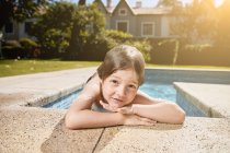 Niedliches lächelndes Kind lehnt am Beckenrand und ruht sich nach dem Schwimmen an einem sonnigen Tag aus — Stockfoto