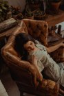 From above of peaceful female sitting in shabby leather chair while relaxing at home — Stock Photo