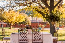 Véranda spacieuse avec assiettes verres à vin et couverts placés sur des tables décorées de fleurs fraîches pour la célébration du mariage — Photo de stock