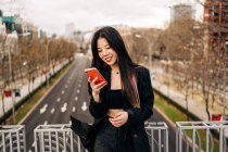Lunghi capelli bruna donna asiatica utilizzando il telefono cellulare in strada — Foto stock