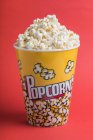Ciotola piena di popcorn su sfondo rosso — Foto stock