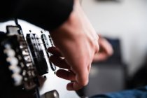 Vista lateral de bajo ángulo del guitarrista ciego concentrado tocando instrumento de música mientras ensayaba melodía en casa - foto de stock
