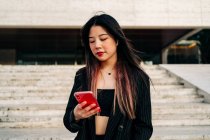 Lange Haare brünett asiatische Frau mit Handy auf der Straße — Stockfoto