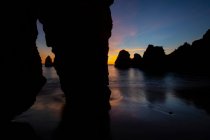 Picturesque view of rocky formations in ocean under cloudy sky at night at Praia do Camilo in Algarve, Portugal — Stock Photo