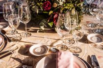 Зверху подається святковий стіл з кришталевими келихами столярна серветка на тарілці біля букету свіжих квітів на весілля — стокове фото