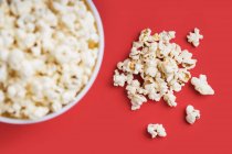 Schüssel voller Popcorn auf rotem Hintergrund — Stockfoto