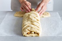 Cultivez une femme chef méconnaissable préparant de délicieuses pâtisseries aux pommes avec de la pâte tressée douce et des tranches de fruits à la maison — Photo de stock