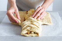 Crop unrecognizable female chef preparing delicious apple pastry with soft braided dough and fruit slices in house — Stock Photo