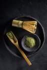 Ложка с сушеными листьями чая маття на черной посуде с часеном для традиционной восточной церемонии — стоковое фото