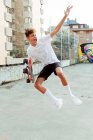 Guapo caucásico adolescente con monopatín saltando y gritando en la calle - foto de stock