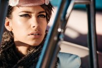 Coltivazione femminile alla moda con fiore sul cappello in automobile, mentre guardando altrove — Foto stock