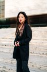 Довге волосся брюнетка азіатська жінка стоїть на сходах і дивиться на камеру — стокове фото