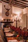 Interno della sala da pranzo con tavolo in legno con posate e piatti decorati con fiori per la cena — Foto stock