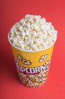 Top view bowl full of popcorn on a red background — Stock Photo