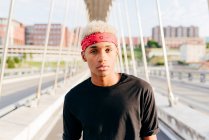 Handsome black boy with headscarf standing in the middle of the bridge looking at camera — Stock Photo