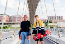 Two handsome teenage boys with skateboard standing on the bridge — Stock Photo