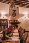 Інтер'єр їдальні з дерев'яним столом з столовими приборами та тарілками, прикрашеними квітами на вечерю — стокове фото