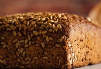 Смачний хліб з цільнозерновим на обробній дошці на столі — стокове фото