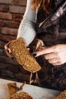 Crop anonimo panettiere femminile dimostrando pane fresco morbido con semi croccanti a tavola in panetteria — Foto stock