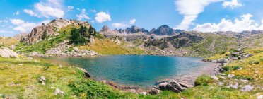 Magnifique paysage de montagnes rocheuses rugueuses entourant un lac bleu calme sous un ciel bleu clair par une journée d'été ensoleillée dans les Pyrénées catalanes — Photo de stock