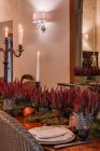 Interieur des Esszimmers mit Holztisch mit Besteck und mit Blumen dekorierten Tellern zum Abendessen — Stockfoto