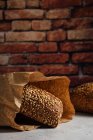 Вкусный цельный хлеб с коричневой корочкой и семечками подсолнечника на столе при дневном свете — стоковое фото