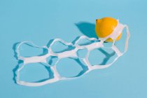 Helle ganze reife und saftige Zitronen zwischen dünnen Plastikverpackungsringen mit Löchern — Stockfoto