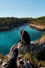 Beautiful view of beach, bay of turquoise blue sea water, with clear skies, sitting on cliff watching feet, Majorca island Spain., — Stock Photo