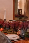Interior del comedor con mesa de madera con cubiertos y platos decorados con flores para la cena - foto de stock
