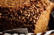 Close-up de saboroso pão cortado com crosta marrom e sementes de girassol crocantes no topo na cesta de vime — Fotografia de Stock