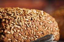 Смачний хліб з цільнозерновим на обробній дошці на столі — стокове фото