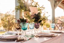 Close-up de mesa festiva servida com copos de cristal guardanapo de talheres na placa perto de cacho de flores frescas para casamento e cartão de menu — Fotografia de Stock