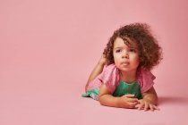 Adorable toddler child in dress with curly hair looking away leaning with hands on floor — Stock Photo