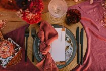 Верхний вид декоративной тарелки с красочной салфеткой с узлом и белой поздравительной открыткой на столе во время свадебного торжества — стоковое фото